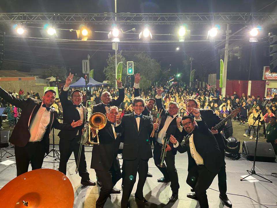 La Banda del Papi tocando de noche sobre el escenario, con el público de pie frente a ellos