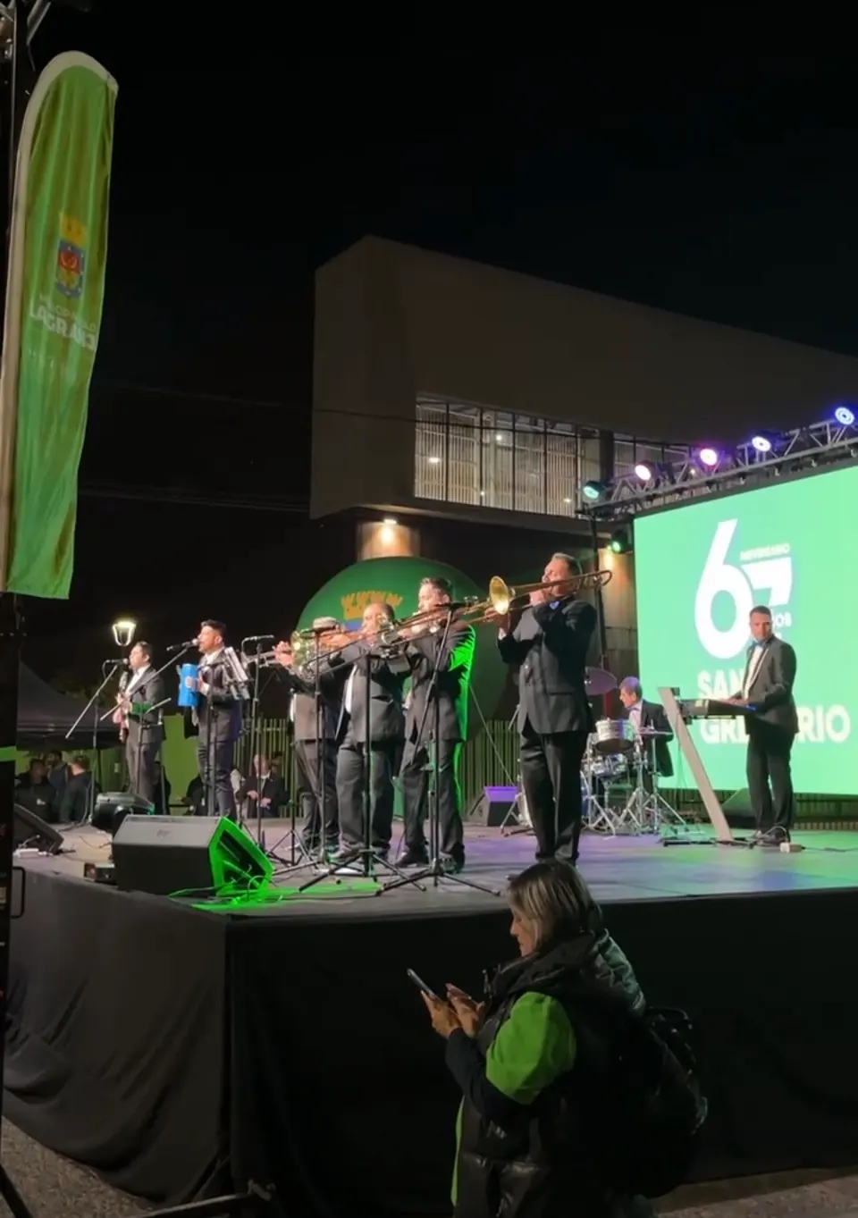 La Banda del Papi sobre un escenario al aire libre, iluminada por una pantalla LED verde