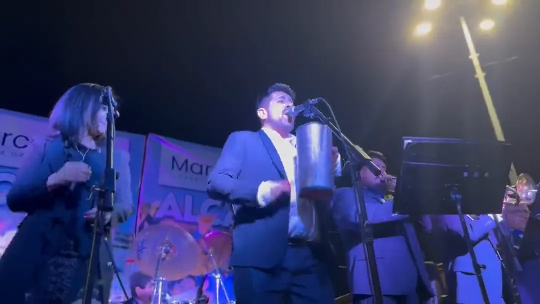 Cantante y músicos de La Banda del Papi tocando en vivo sobre el escenario, vistos desde el público