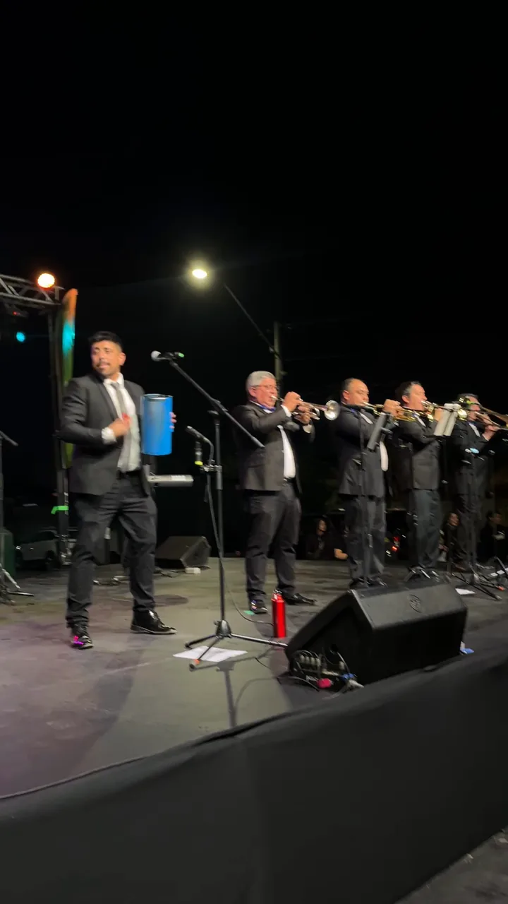 La Banda del Papi tocando en vivo sobre el escenario, video de fondo en bucle